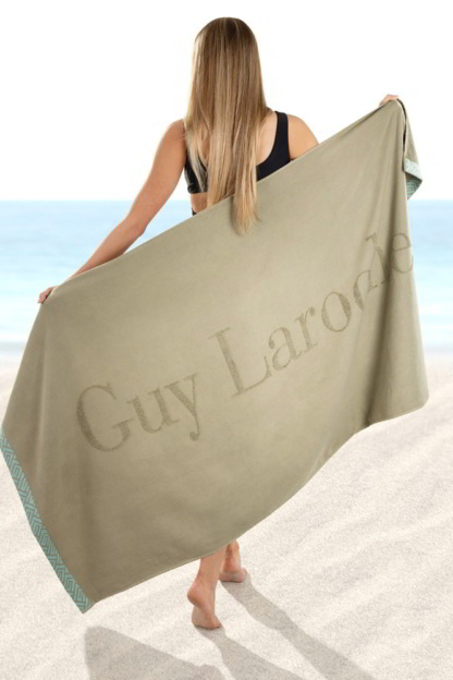Μοντέρνα πετσέτα θάλασσας Guy Laroche Echo Khaki. Διπλής όψης και υψηλής ποιότητας, κατασκευασμένη από 100% βαμβάκι. Μονόχρωμη, σε πράσινο χρωματισμό, με ανάγλυφο λογότυπο της Guy Laroche και λεπτή, ζακάρ φάσα στα δύο της άκρα. 90 x 180 εκατοστά.