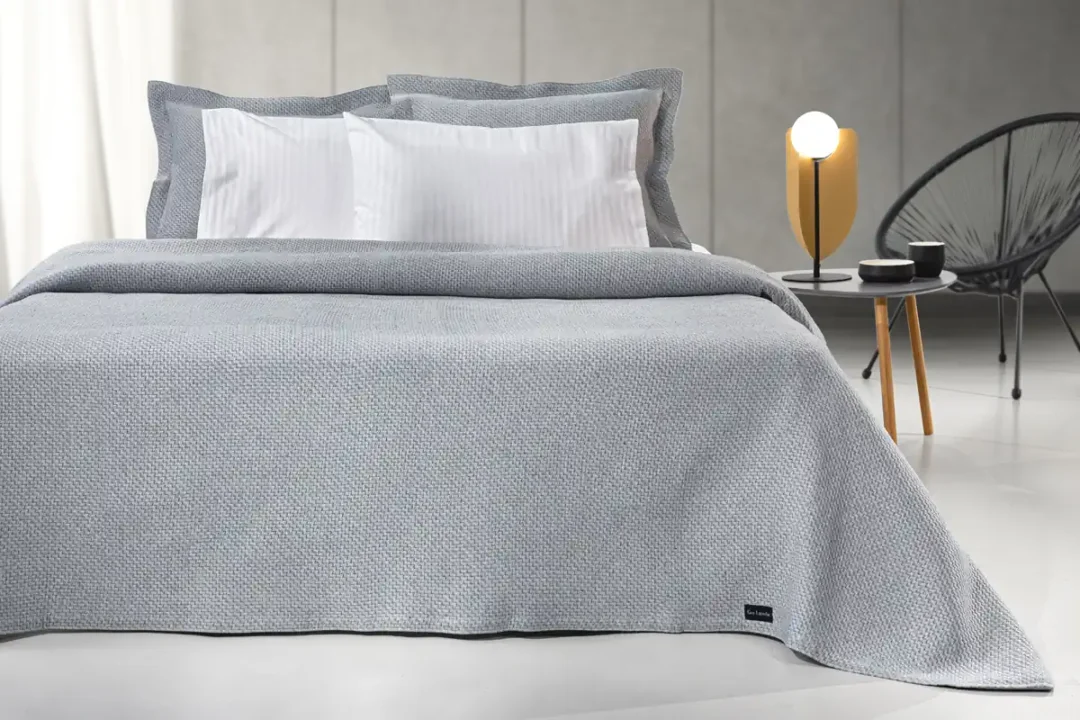 Ανοιξιάτικη κουβέρτα Slalom Anthracite της εταιρίας Guy Laroche Paris. Μονόχρωμη, jacquard, κατασκευασμένη από 60% βαμβάκι και 40% polyester, 180 x 260 εκατοστά.